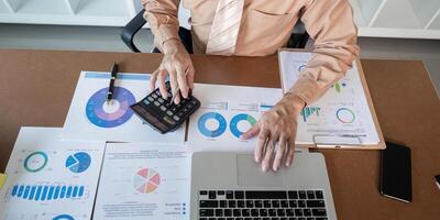 Analyzing financial data using a calculator and laptop in an office environment photo