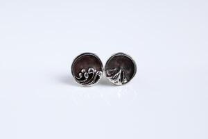 Round silver earrings with a mountain and sea design on a white background. Handmade jewelry. photo