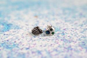 Silver handmade earrings with gemstones in shell and starfish shapes on sparkly background. photo