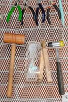 Collection of hand tools displayed on an jewelry workshop wall, featuring hammers and pliers. photo