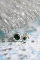 hecho a mano plata en forma de corazon semental pendientes con verde piedras preciosas en un Navidad brillante antecedentes. foto
