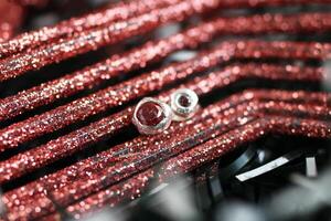 plata pendientes con redondo rojo piedras preciosas en rojo Brillantina Navidad antecedentes. hecho a mano joyas. foto