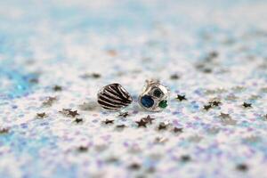 Silver handmade earrings with gemstones in shell and starfish shapes on sparkly background. photo