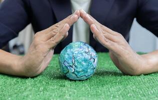 Hands of business man over the earth model on a green table to protect nature. Save and care World for sustainable photo