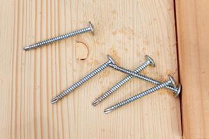five steel screws on a wooden plank photo