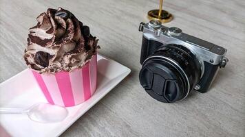 Mirrorless camera in retro style and cake or croissant on wooden table. photo