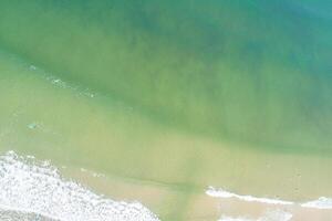 turquoise seawater on the shore of a beach, aerial top view from a drone photo