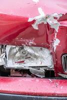 front view of the side of a red car dented by traffic impact photo