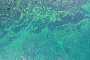 close-up aerial drone top view of water and seabed at the shore of a beach, textured background marine concept photo