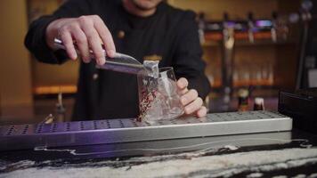bartender pouring ice into a glass standing on the bar counter, mixology video