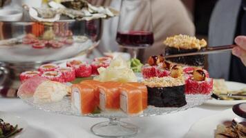 Guests Sharing Sushi Rolls with Chopsticks at a Party Table video
