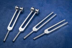 Set of weighted and unweighted metal tuning forks used for tuning musical instruments, sound therapy, chakra healing or relaxation. photo