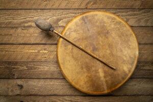 handmade, native American style, shaman frame drum covered by goat skin with a beater on a rustic wood photo