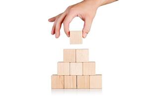 wooden cubes in the form of a pyramid with a hand on an isolate white background photo