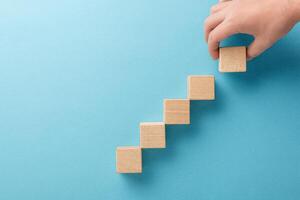wooden cubes in the form of a ladder with a hand on a blue background photo
