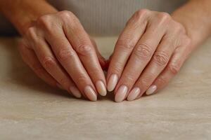 Elegant hands with well manicured nails resting on a neutral countertop. photo