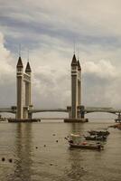 A stunning photogenic Kuala Terengganu drawbridge under a dramatic cloudy sky with structure featuring twin towers and a modern design that nestled against the ocean below. photo