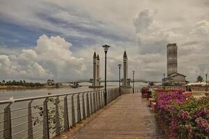 A stunning photogenic Kuala Terengganu drawbridge under a dramatic cloudy sky with structure featuring twin towers and a modern design that nestled against the ocean below. photo