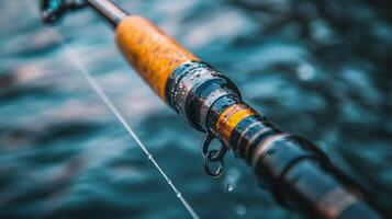 Close-up of a fishing rod with droplets resting on its surface near calm water photo