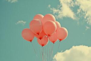 Pink balloons float against a bright blue sky with fluffy white clouds in a joyful outdoor setting photo