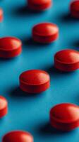 Red capsules scattered on a vibrant blue surface highlighting texture and detail photo