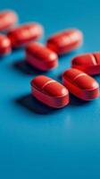 Red capsules scattered on a vibrant blue surface highlighting texture and detail photo
