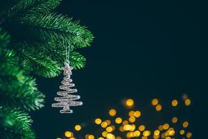 Silver spiral christmas tree ornament hanging from a green branch with a golden bokeh effect in the background, creating a festive and magical atmosphere photo