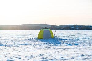 Ice fishing. Tent and fishing auger, ice auger on snowy lake in winter, winter pastime, hobby, relaxation photo