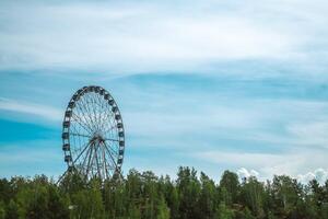 Ferris wheel with cabins against the background of the sky and clouds, amusement park with copy space photo