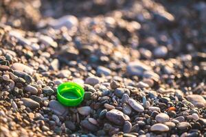 plastic bottle cap on the beach, environmental pollution photo