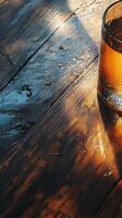 Golden drink reflecting sunlight on rustic wooden table surface photo