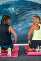 vertical Two senior women in sportswear enjoying a break on yoga mats during gym class photo
