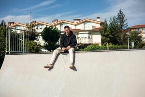 copyspace Skater sitting on half-pipe edge staring at the camera while holding skateboard photo