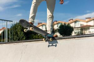 Close-up of a skater's legs on the board at the edge of the half-pipe on a sunny day photo