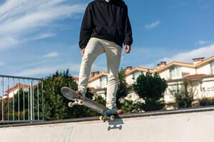 Unrecognizable skater poised on the edge of half-pipe ready to launch down the ramp photo