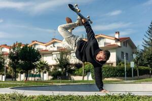 Skater performing an aerial trick while balancing upside down on the edge of the skate park bowl photo