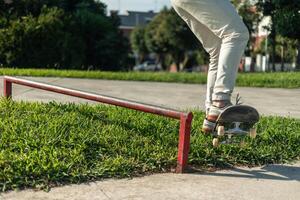 Close-up of skater's legs finishing a grind on a red rail at the skate park during a session photo