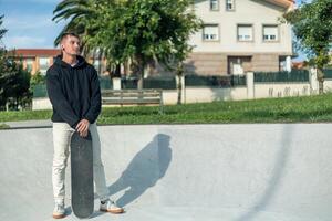 copyspace Reflective skater standing with skateboard, looking off into the distance photo