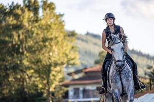 copyspace young woman rider gallops towards the camera while training with her horse at the ranch photo