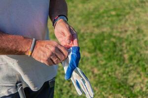 closeup of senior golfer adjusting glove before starting golf game photo