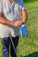 vertical closeup of senior golfer adjusting glove in preparation for game photo