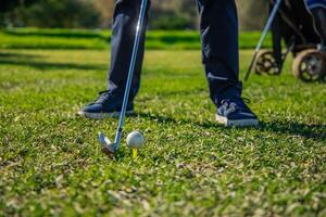 closeup of senior golfer's legs positioned with club ready to strike ball on tee photo