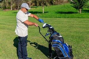 senior golfer selecting the right club from bag for next shot photo