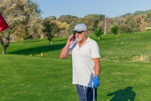 copyspace senior golfer making business call with smartphone during golf game photo