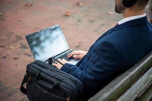 Unrecognized businessman working outdoors on company projects with laptop photo