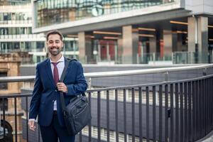 Smiling businessman walking in city with briefcase photo