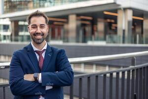 Smiling businessman standing with arms crossed in urban setting photo