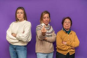 Three generations of women showing strength and defiance against purple background photo