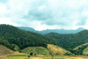 landscape of rolling green hills and valleys under a bright blue sky with scattered white clouds. Landmark hills of Mae La Luang. Mae Hong Son of Thailand. photo