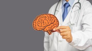 Doctor in uniform holding a red brain symbol while standing on a gray background photo